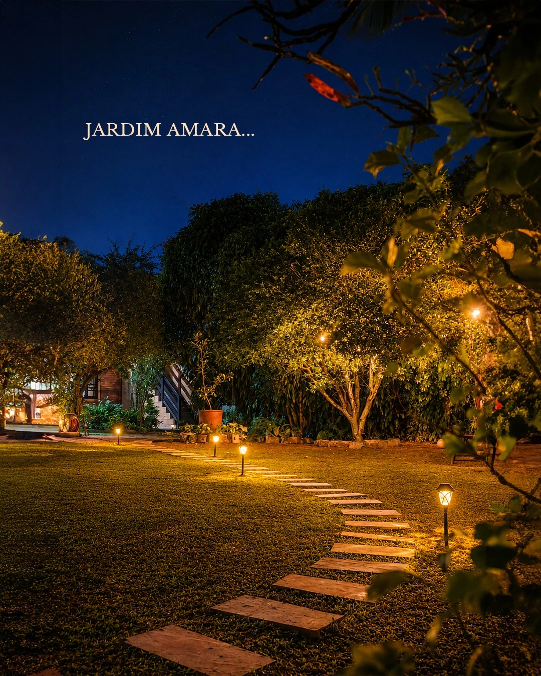 Jardim do AMARA iluminado à noite, com caminho entre as árvores